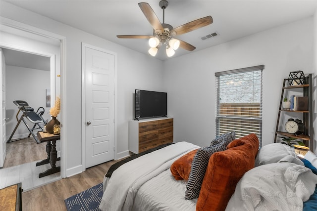 bedroom with baseboards, a ceiling fan, wood finished floors, and visible vents