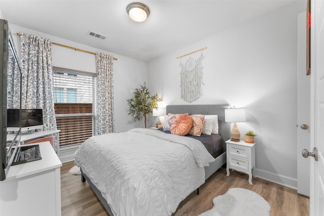 bedroom featuring baseboards, visible vents, and light wood finished floors