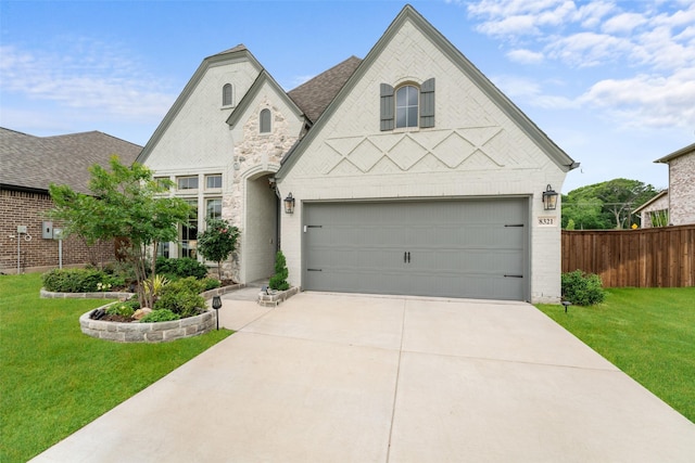 french country inspired facade featuring fence, a garage, driveway, and a front yard