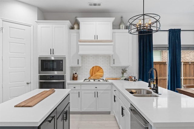 kitchen with a sink, appliances with stainless steel finishes, light countertops, and visible vents