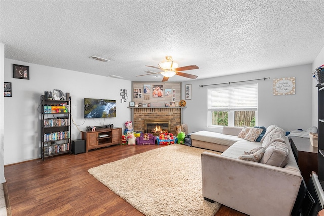 4212 Selina Ct, Arlington, TX 76016 - living room featuring wood finished floors, ceiling fan, a textured ceiling, and a brick fireplace