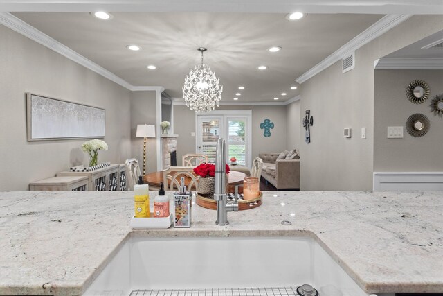 kitchen featuring an inviting chandelier, ornamental molding, open floor plan, recessed lighting, and a sink