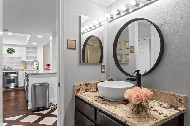 bathroom with vanity, recessed lighting, a textured wall, and tasteful backsplash
