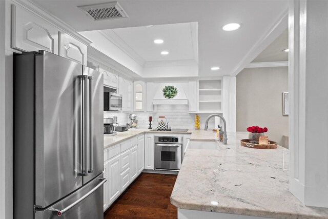 kitchen featuring open shelves, ornamental molding, a peninsula, a sink, and appliances with stainless steel finishes