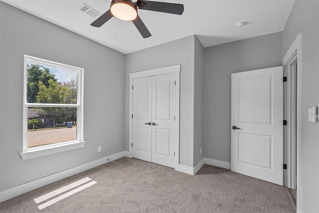 unfurnished bedroom featuring visible vents, carpet floors, a closet, baseboards, and ceiling fan