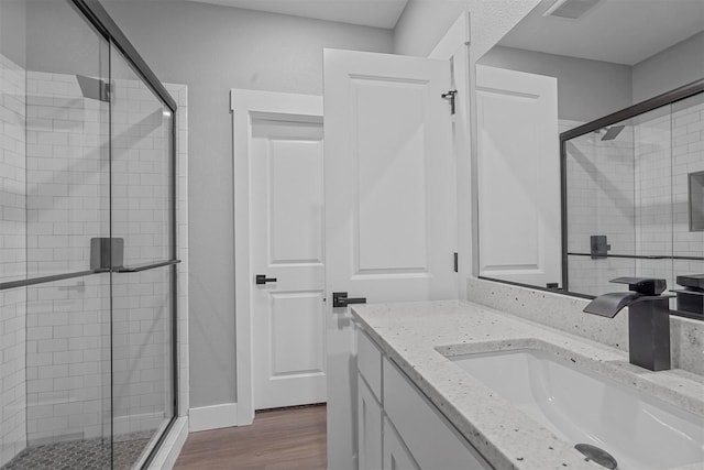 bathroom with vanity, wood finished floors, visible vents, and a shower stall