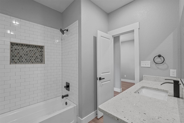 bathroom featuring baseboards,  shower combination, wood finished floors, and vanity