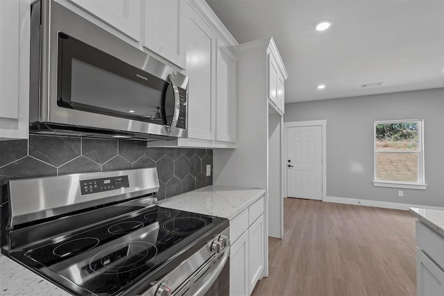 kitchen featuring light wood finished floors, white cabinets, light stone countertops, and stainless steel appliances