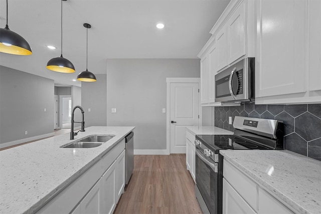 kitchen with light wood-style floors, white cabinetry, tasteful backsplash, a sink, and stainless steel appliances