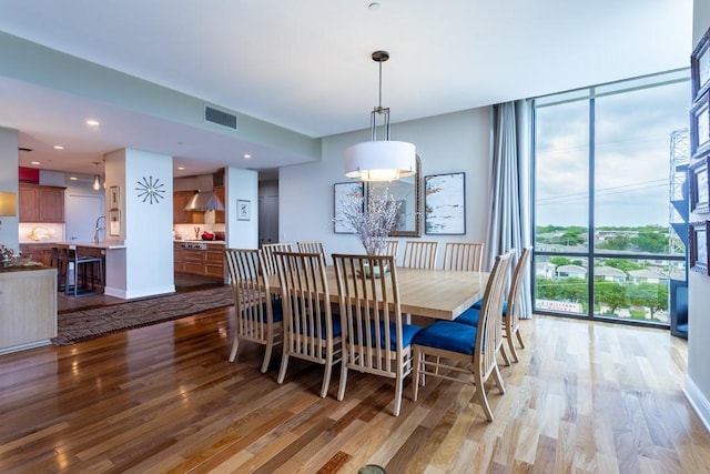 dining space featuring visible vents, light wood-style floors, and a wall of windows