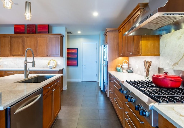 kitchen with a sink, stainless steel appliances, brown cabinets, and wall chimney exhaust hood