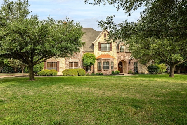 tudor house with brick siding, a standing seam roof, and a front lawn