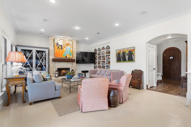 living room with crown molding, arched walkways, a fireplace, and recessed lighting