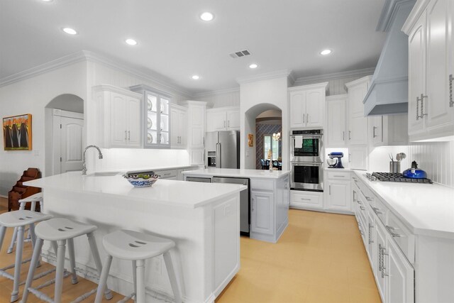 kitchen with a sink, a peninsula, a breakfast bar area, arched walkways, and stainless steel appliances