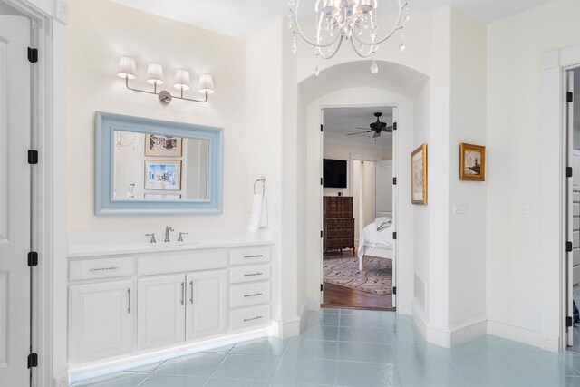 bathroom featuring tile patterned flooring, vanity, ceiling fan with notable chandelier, baseboards, and ensuite bathroom