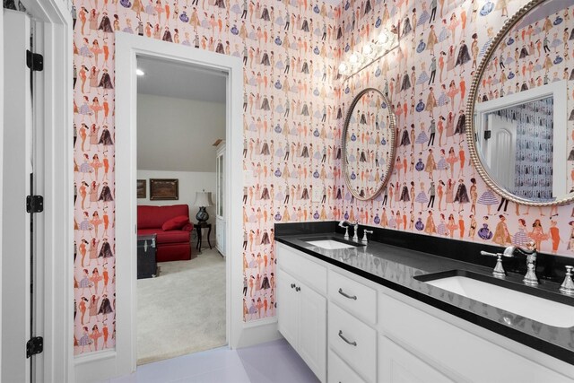 bathroom featuring a sink, wallpapered walls, and double vanity