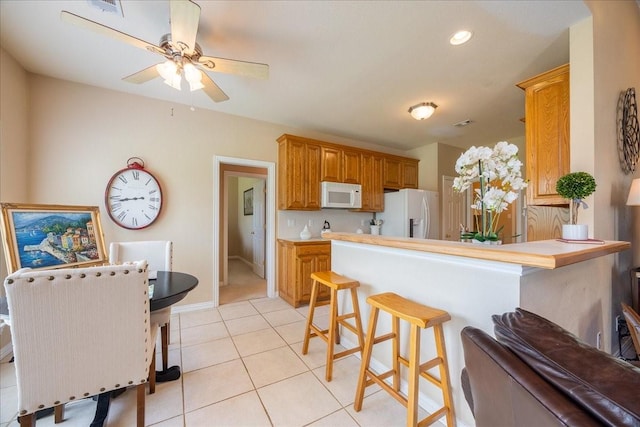 265 Old Spanish Trl, Valley View, TX 76272 - kitchen featuring light tile patterned flooring, a breakfast bar, white appliances, a ceiling fan, and a peninsula