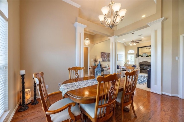 265 Old Spanish Trl, Valley View, TX 76272 - dining space featuring wood finished floors, baseboards, ceiling fan with notable chandelier, a glass covered fireplace, and ornate columns