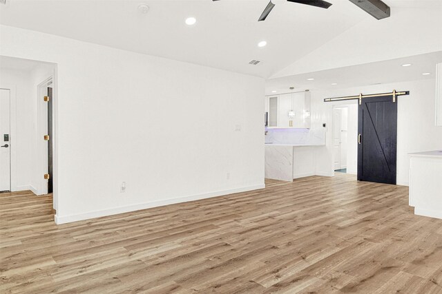 unfurnished living room featuring lofted ceiling with beams, a barn door, a ceiling fan, recessed lighting, and light wood-type flooring