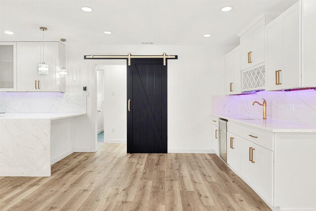 kitchen with white cabinets, recessed lighting, a sink, and light wood-style floors