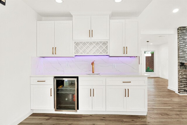 bar with decorative backsplash, wet bar, a sink, light wood finished floors, and beverage cooler