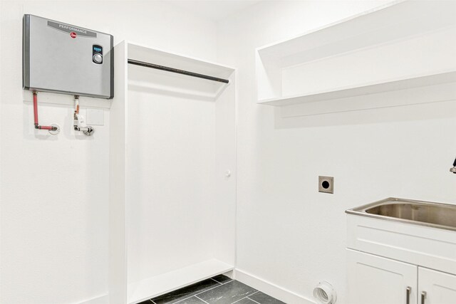 laundry room with a sink, baseboards, hookup for an electric dryer, and cabinet space