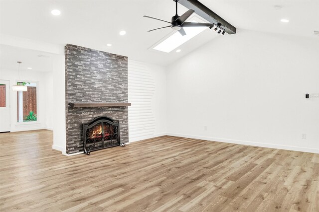 unfurnished living room with a ceiling fan, a large fireplace, wood finished floors, lofted ceiling with skylight, and recessed lighting