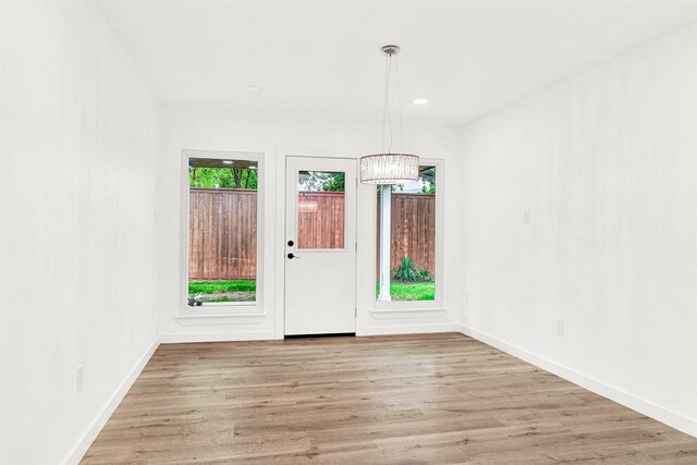 foyer entrance with light wood-type flooring, baseboards, and a chandelier