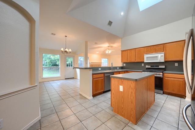 9104 Chesapeake Ln, Mckinney, TX 75071 - kitchen featuring appliances with stainless steel finishes, light tile patterned floors, a peninsula, high vaulted ceiling, and a sink