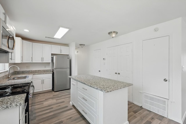 kitchen featuring visible vents, light wood-type flooring, white cabinets, a sink, and appliances with stainless steel finishes