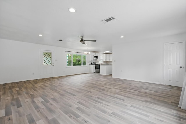 unfurnished living room with ceiling fan with notable chandelier, recessed lighting, and light wood-style flooring
