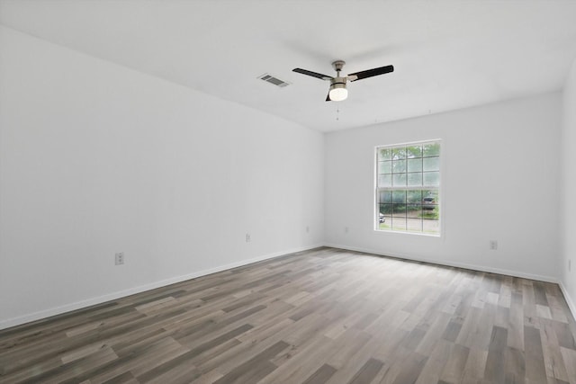 empty room featuring a ceiling fan, baseboards, visible vents, and wood finished floors