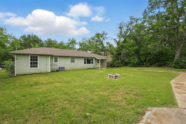 back of property with central AC unit, a yard, and an outdoor fire pit