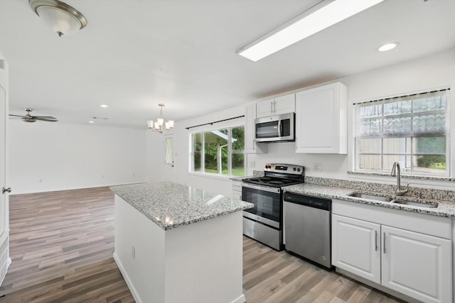 kitchen featuring a center island, white cabinets, a sink, light wood-style flooring, and stainless steel appliances