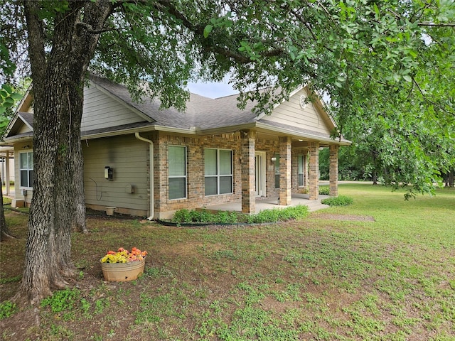 view of property exterior featuring a shingled roof, a yard, and a patio area