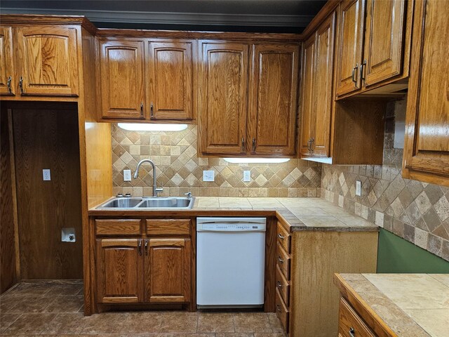 kitchen with white dishwasher, brown cabinetry, a sink, and tasteful backsplash