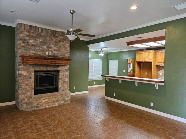 unfurnished living room with baseboards, ornamental molding, ceiling fan, and a fireplace