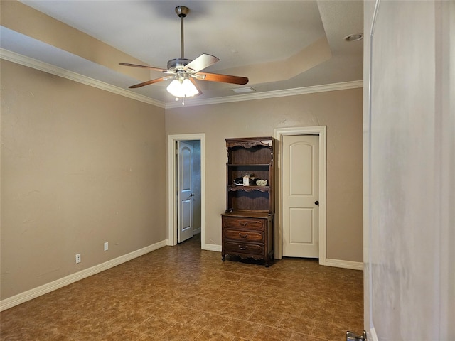 unfurnished bedroom featuring baseboards, ornamental molding, ceiling fan, and a tray ceiling