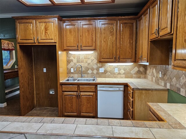 kitchen with white dishwasher, decorative backsplash, brown cabinetry, and a sink