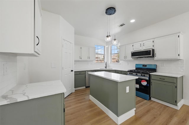 kitchen featuring appliances with stainless steel finishes, light wood finished floors, a sink, and visible vents