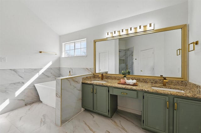 full bath featuring double vanity, a freestanding tub, a sink, and marble finish floor