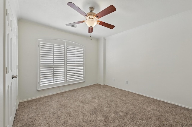 carpeted spare room with crown molding, baseboards, a ceiling fan, and visible vents