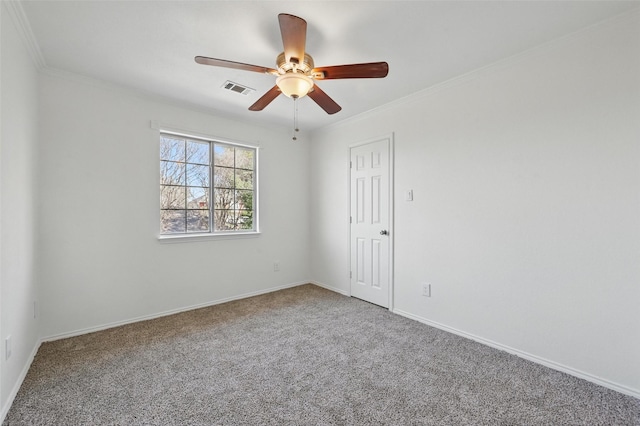 carpeted spare room featuring visible vents, a ceiling fan, baseboards, and crown molding
