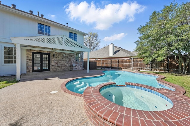 view of pool with french doors, a patio, a pool with connected hot tub, and a fenced backyard