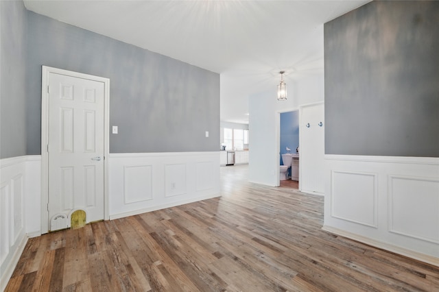 spare room featuring wood finished floors, a wainscoted wall, and a decorative wall