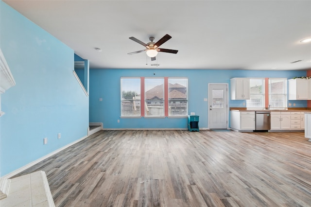 unfurnished living room with ceiling fan, a sink, baseboards, and light wood-type flooring