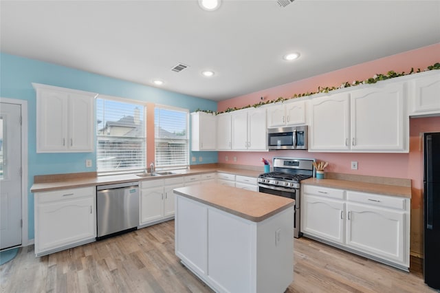 kitchen with appliances with stainless steel finishes, a sink, light countertops, white cabinetry, and visible vents