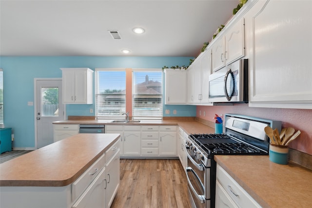 kitchen featuring a sink, light wood-style flooring, appliances with stainless steel finishes, and white cabinets