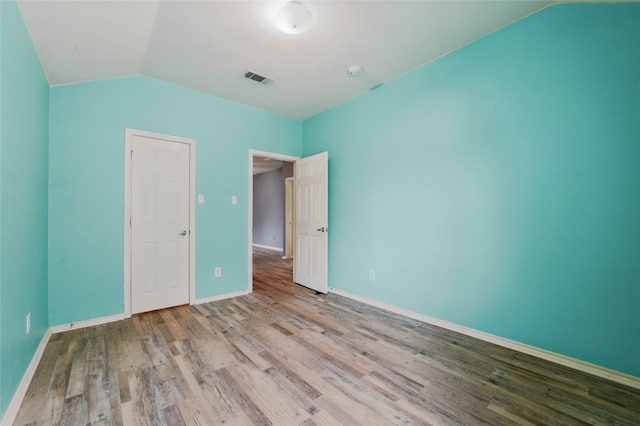 unfurnished bedroom featuring baseboards, visible vents, wood finished floors, and lofted ceiling