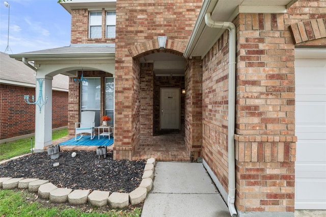 entrance to property with a porch and brick siding